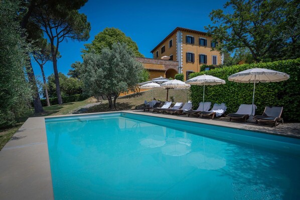 Relax by the serene pool surrounded by lush greenery and comfortable lounge chairs.
