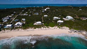 Vista aérea de una zona residencial costera con casas, una playa y aguas turquesas.