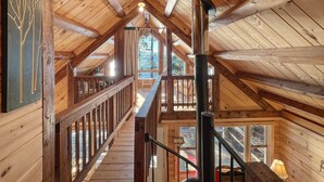 Ein Holzinnenraum mit hoher Decke, einer Treppe und einem Kamin.