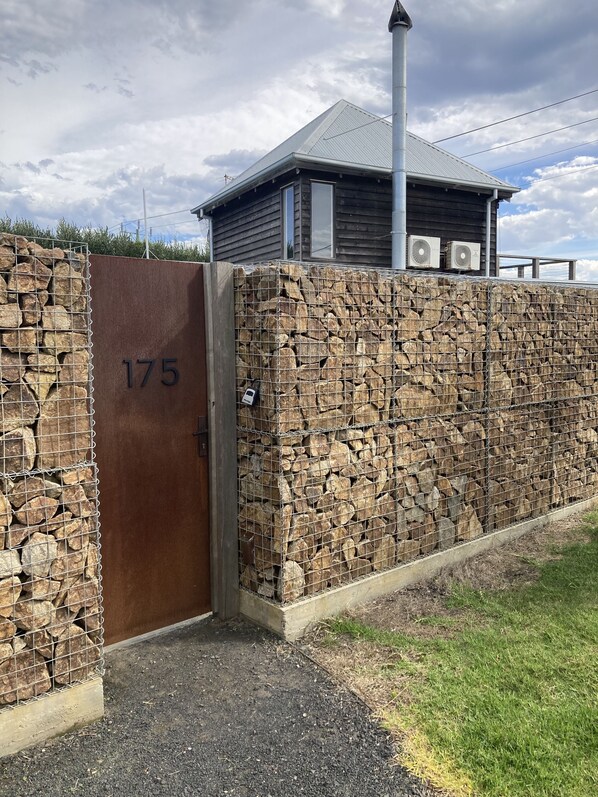 A gated entrance with a stone wall and a metal gate marked with the number 175. - Stylish unquie beach side property with all amenities (Surf Beach)