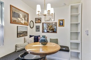 A dining area with a round wooden table, a bench, and a chandelier.