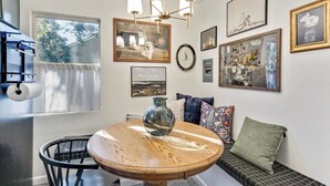 A dining area with a round wooden table, a vase, and a bench with cushions. - Luxe Mountainview Haven | Backyard | Massage* (Provo)
