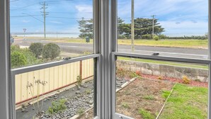 A view from a window with a clear sky, a road, and a grassy area with a yellow building in the foreground.