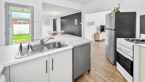 A modern kitchen with a large island, stainless steel appliances, and a sliding glass door leading to a backyard.