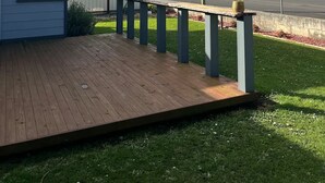 A residential property with a wooden deck, a small house, and a view of a road and distant landscape.