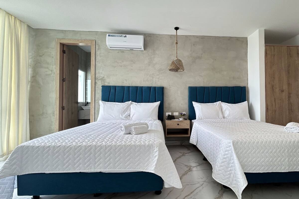 Ein Hotelzimmer mit zwei Betten, einem Holzschrank, einer Klimaanlage und einer Pendelleuchte.