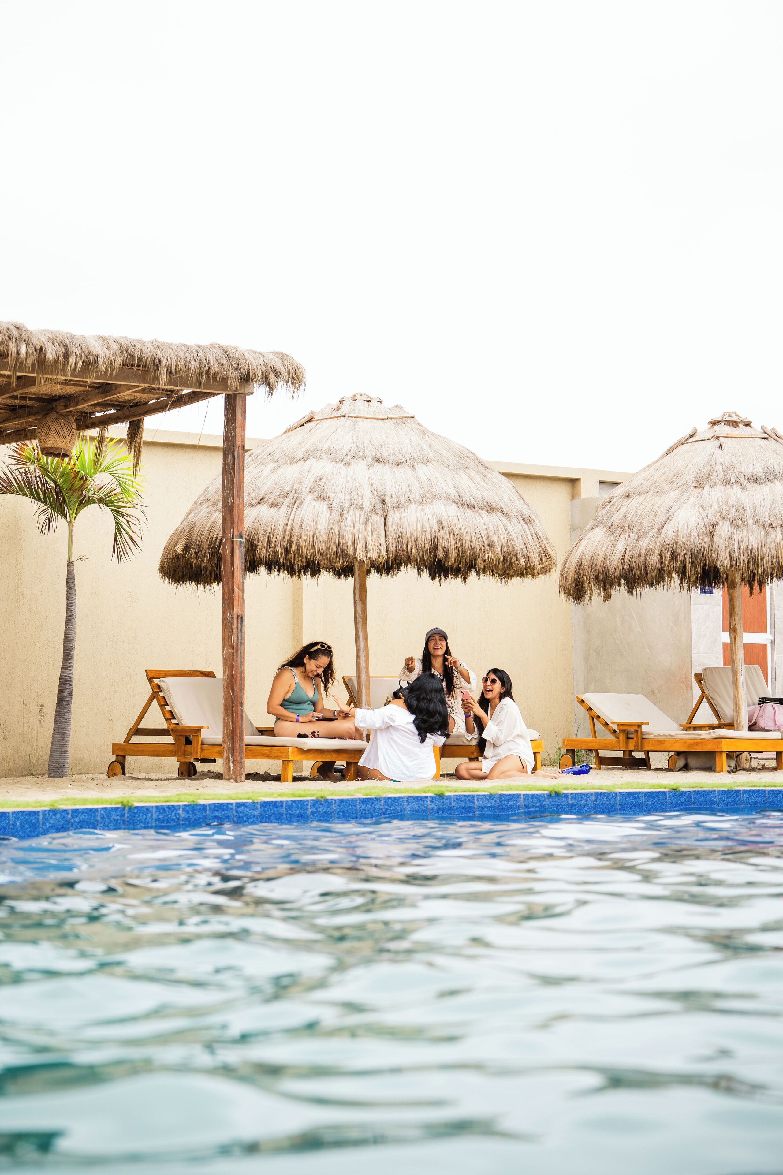 A poolside area with lounge chairs and thatched umbrellas.