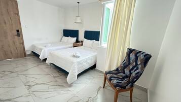 A room with two beds, a chair, a wooden door, and a window with curtains.