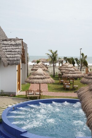 A beachside resort with a swimming pool, thatched umbrellas, and a view of the ocean. - Hotel Presidente Beach Playas  (Playas)
