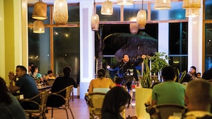 Un restaurant avec des chaises en osier et des lampes suspendues.