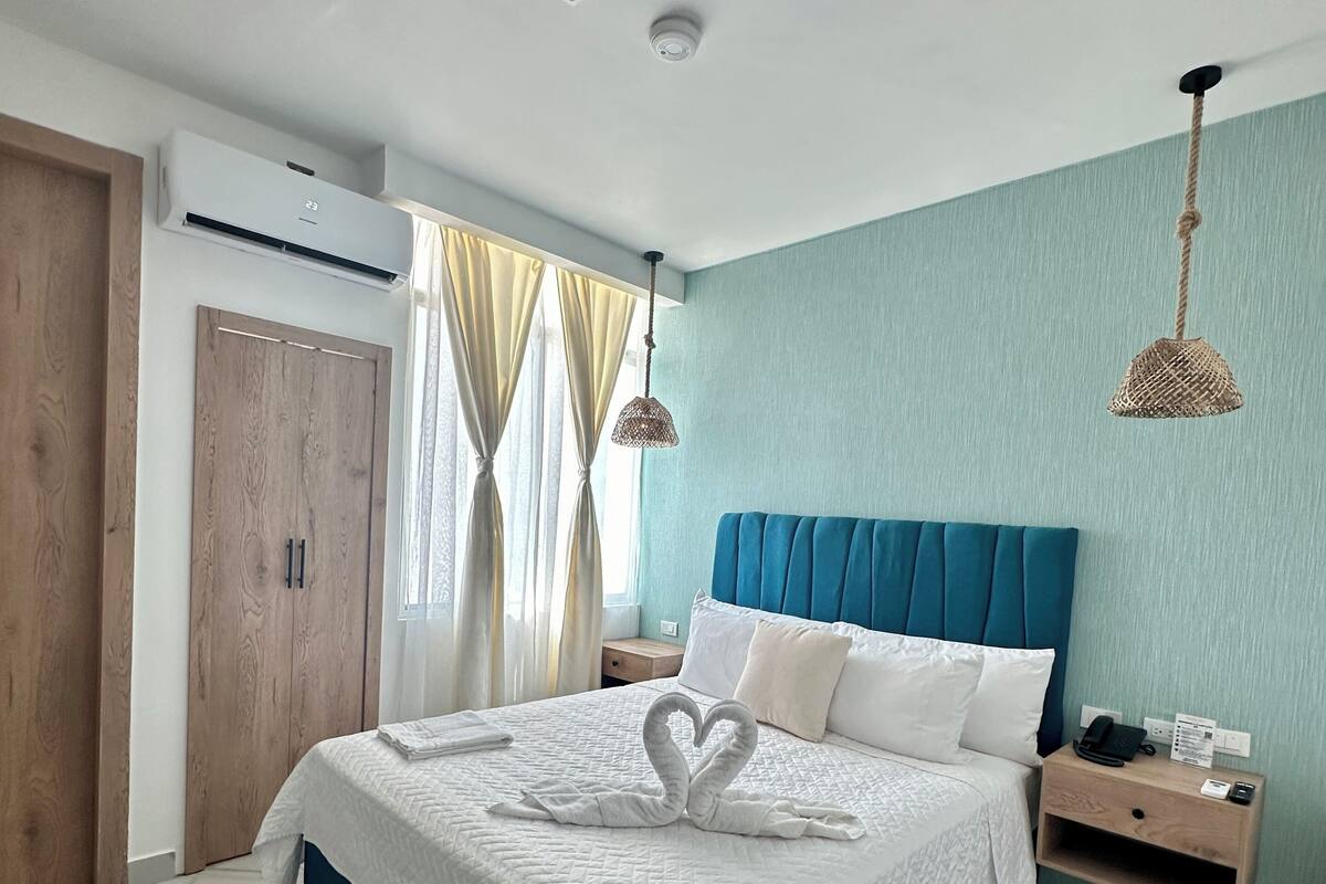 Ein modernes Schlafzimmer mit Bett, Nachttisch, Wand-Klimaanlage und Deckenleuchte.