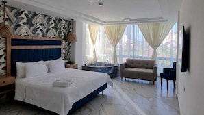 Une chambre spacieuse avec un grand lit, un canapé, une petite table et un jacuzzi.