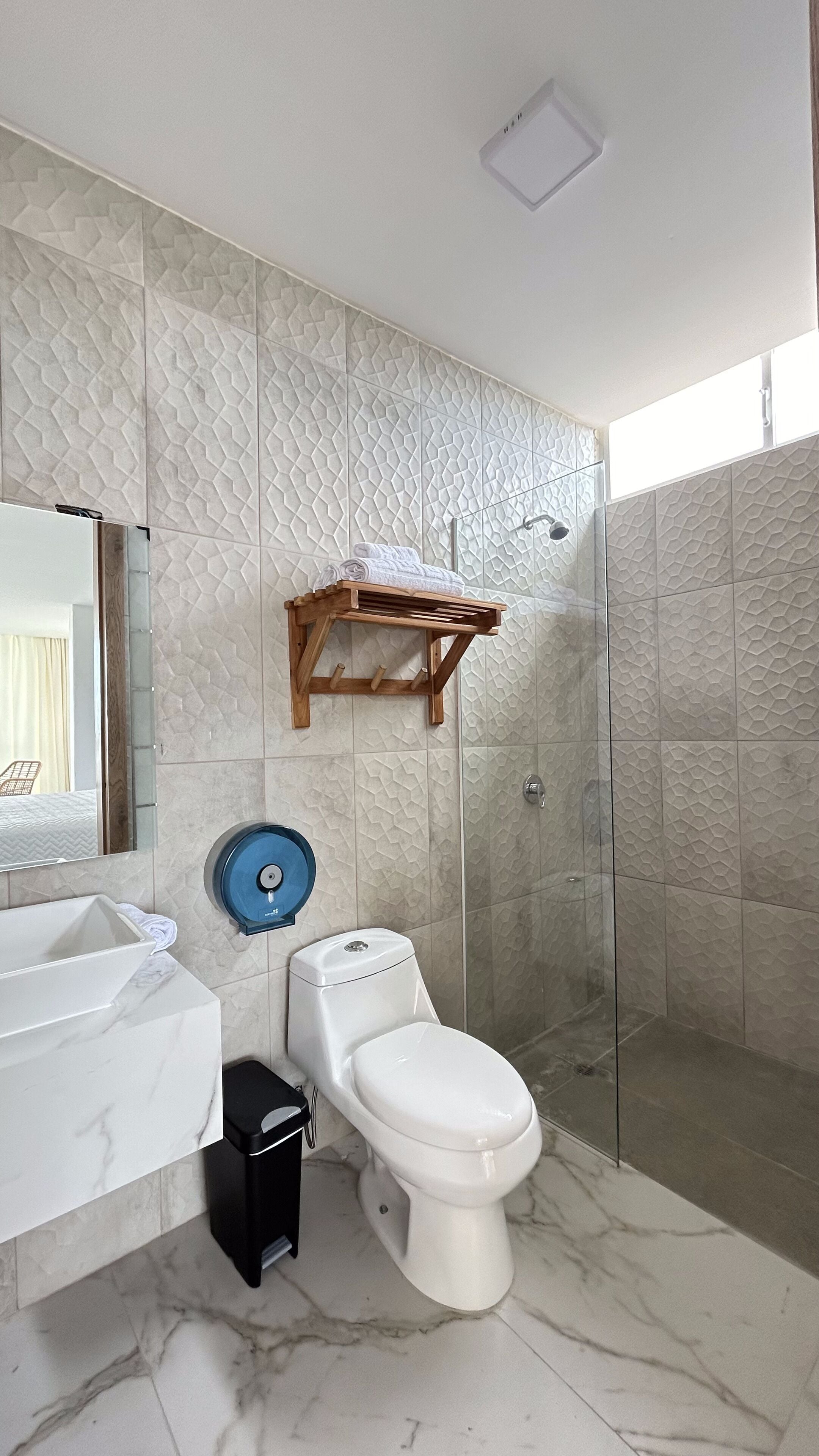 Ein Badezimmer mit Toilette, Waschbecken, Dusche und einem Holzregal.