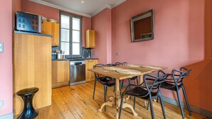 Une cuisine compacte avec des meubles en bois, un lave-vaisselle encastré et un coin repas comprenant une table en bois et des chaises en métal.