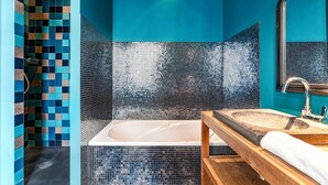 Une salle de bain avec une baignoire, un meuble-lavabo en bois et un grand miroir.