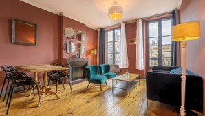 Un salon chaleureux avec une cheminée, une table à manger avec des chaises, un canapé et une lampe.