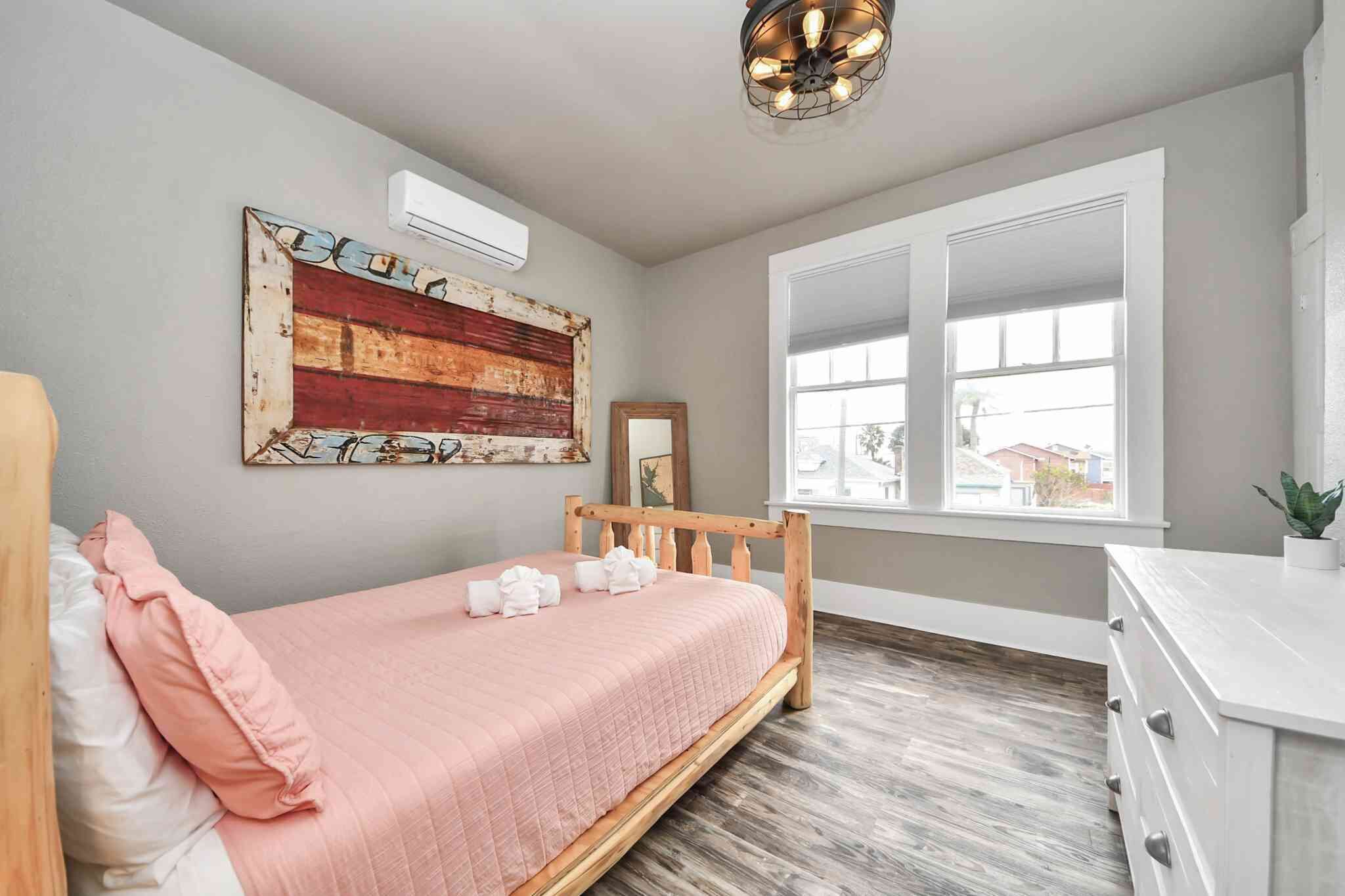 Een slaapkamer met een bed, een raam, een wandairconditioner en een plafondlamp.