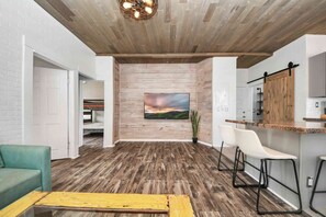 Ein modernes Interieur mit Holzboden, einem an der Wand befestigten Fernseher, einer Bar und einer Sitzecke.