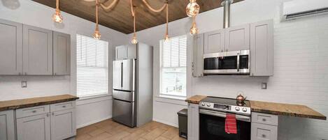 A modern kitchen with grey cabinets, stainless steel appliances, and a wooden ceiling.