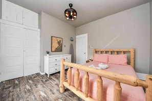 Ein Schlafzimmer mit einem hölzernen Bett, einem weißen Kleiderschrank und einem Deckenventilator.