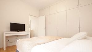 A bedroom with a bed, a TV on a desk, and a wardrobe. - Jardin Public | Bright & Stylish 1BR Apt for 4 Guests (Bordeaux)