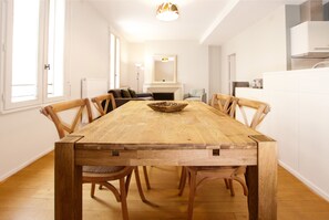 Une salle à manger avec une table et des chaises en bois, une cheminée et une vue sur la cuisine.