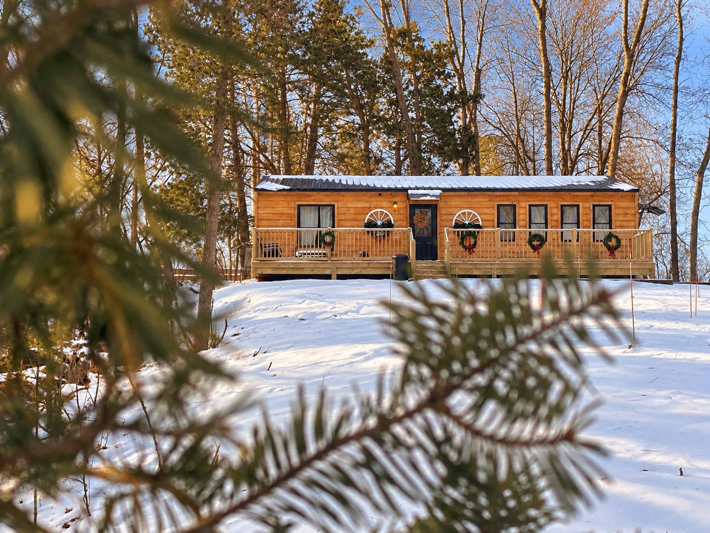 A wooden cabin with a porch, surrounded by trees and snow.