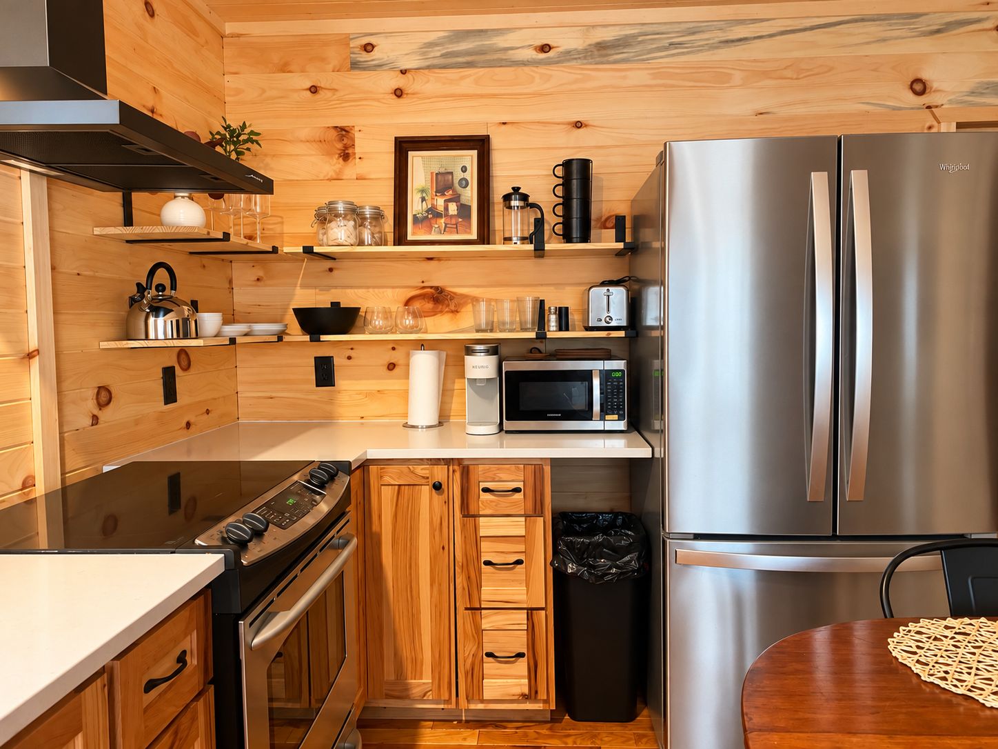 A compact kitchen with a stainless steel refrigerator, a microwave, and a stove.