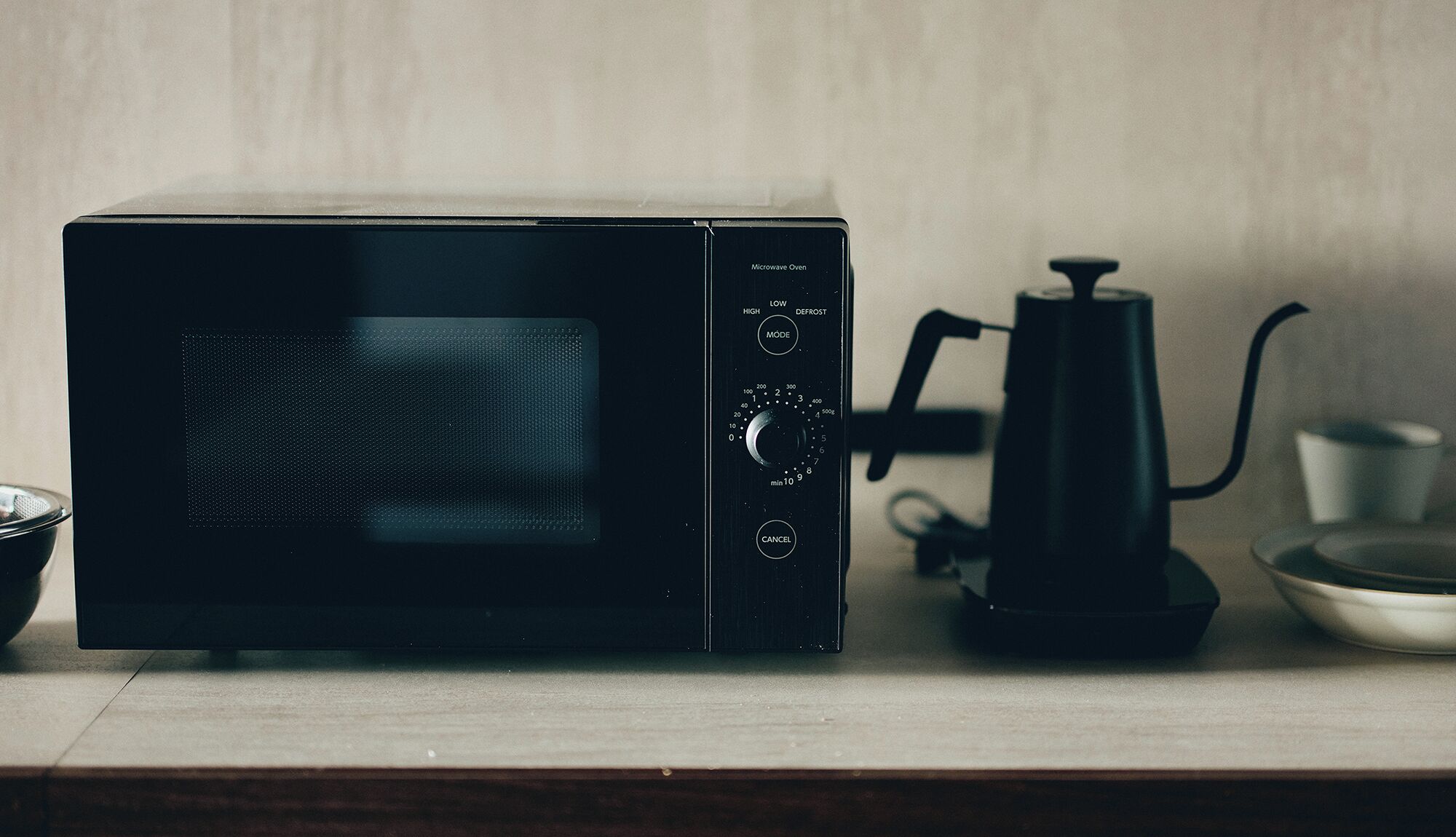 A microwave oven with a digital display, control knobs, and a power cord.