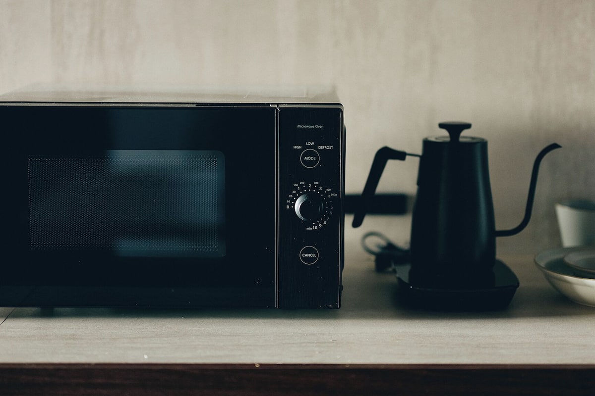 A microwave oven with a digital display, control knobs, and a power cord.