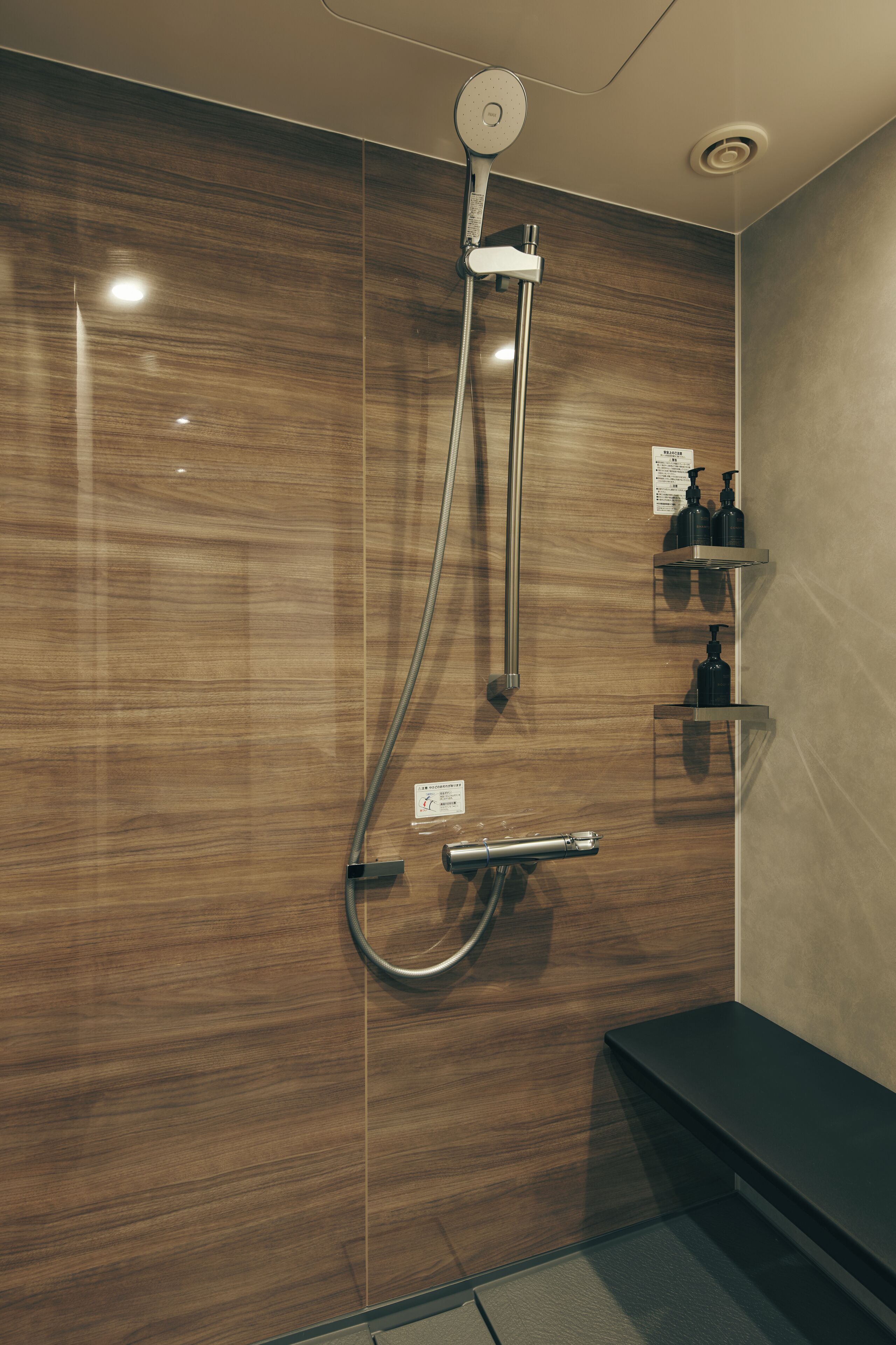 A modern shower with a wooden wall, a handheld showerhead, and a wall-mounted control panel.