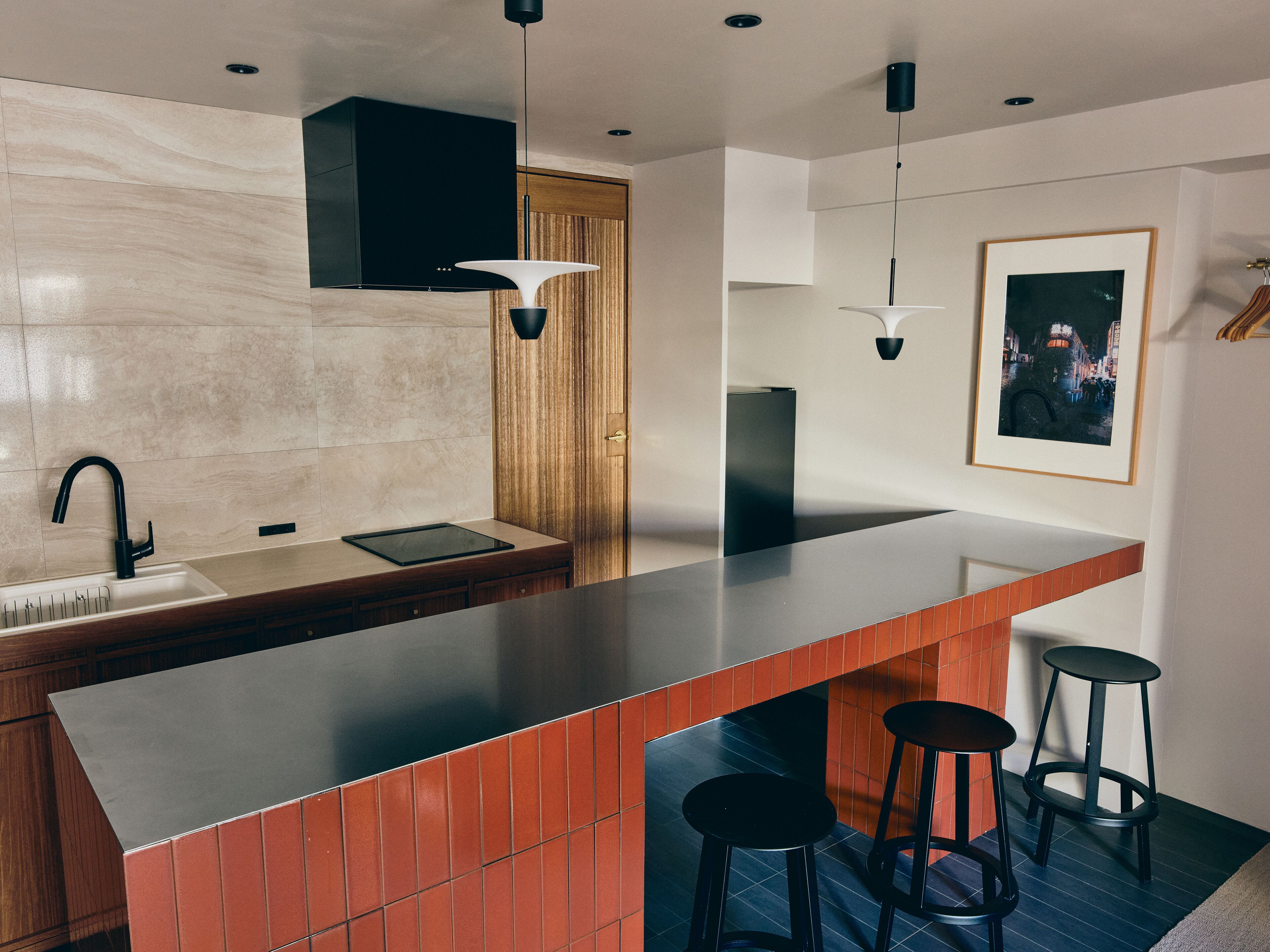 Una cocina moderna con una isla grande, taburetes negros y una puerta de madera.