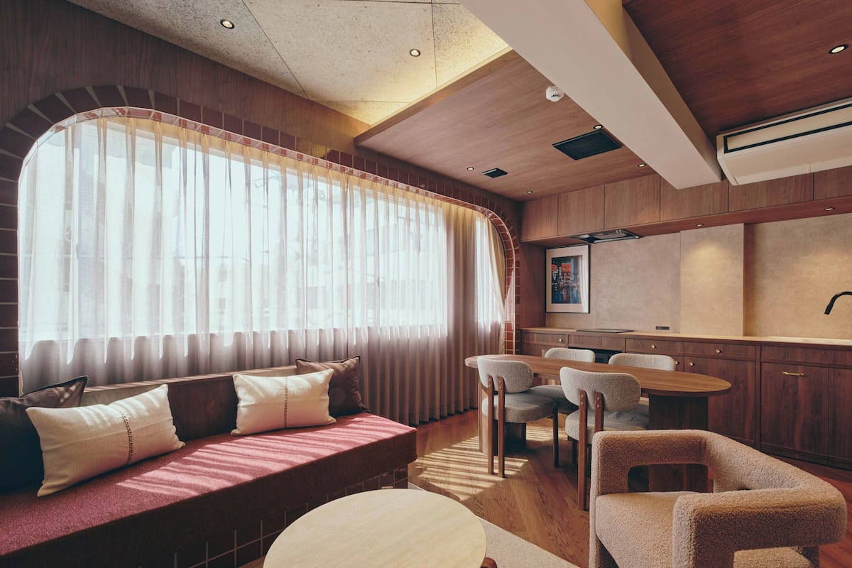 A modern interior with a sofa, dining table, chairs, and a kitchen area.