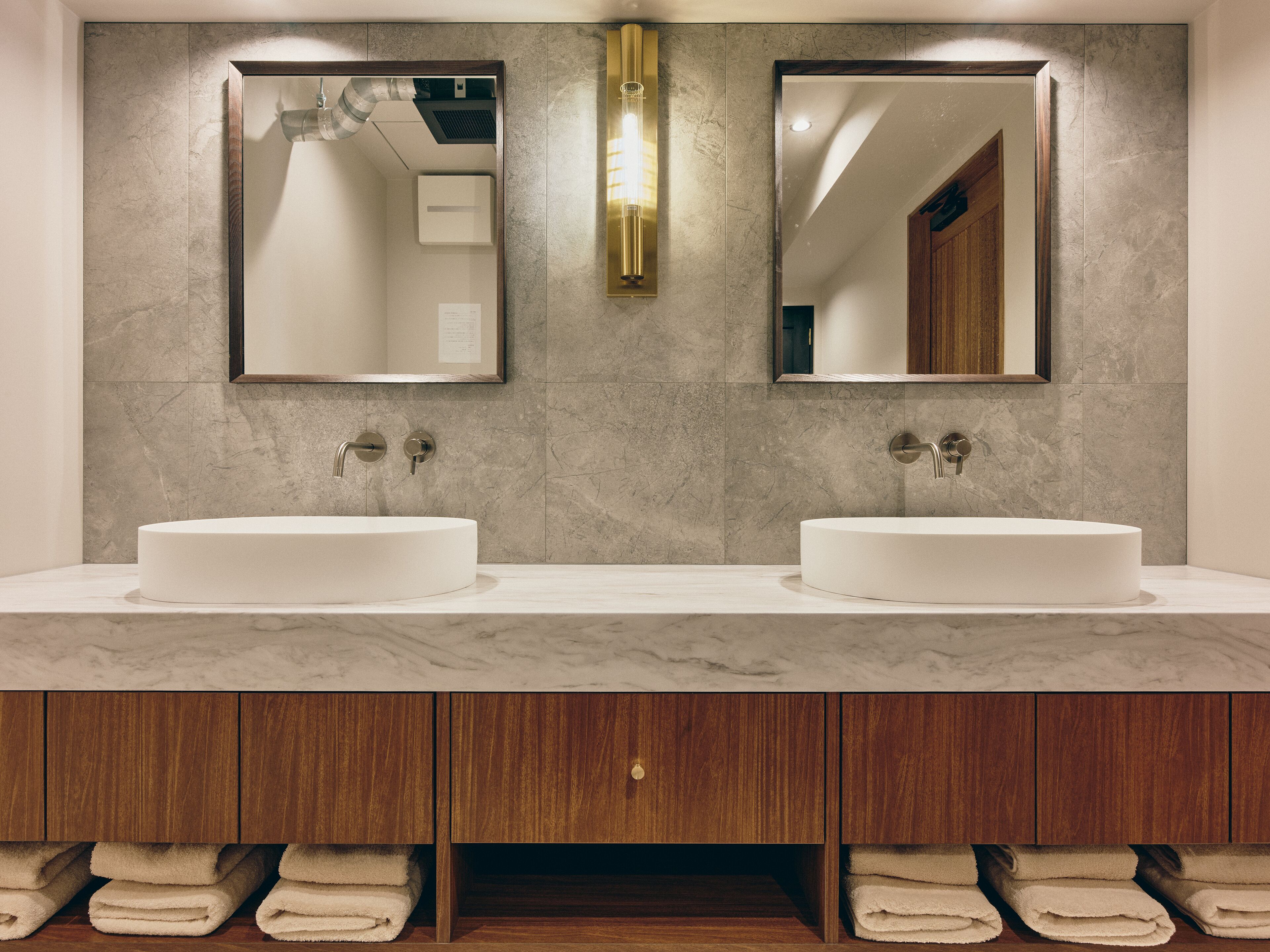 A bathroom with two sinks, a mirror, and a towel rack.