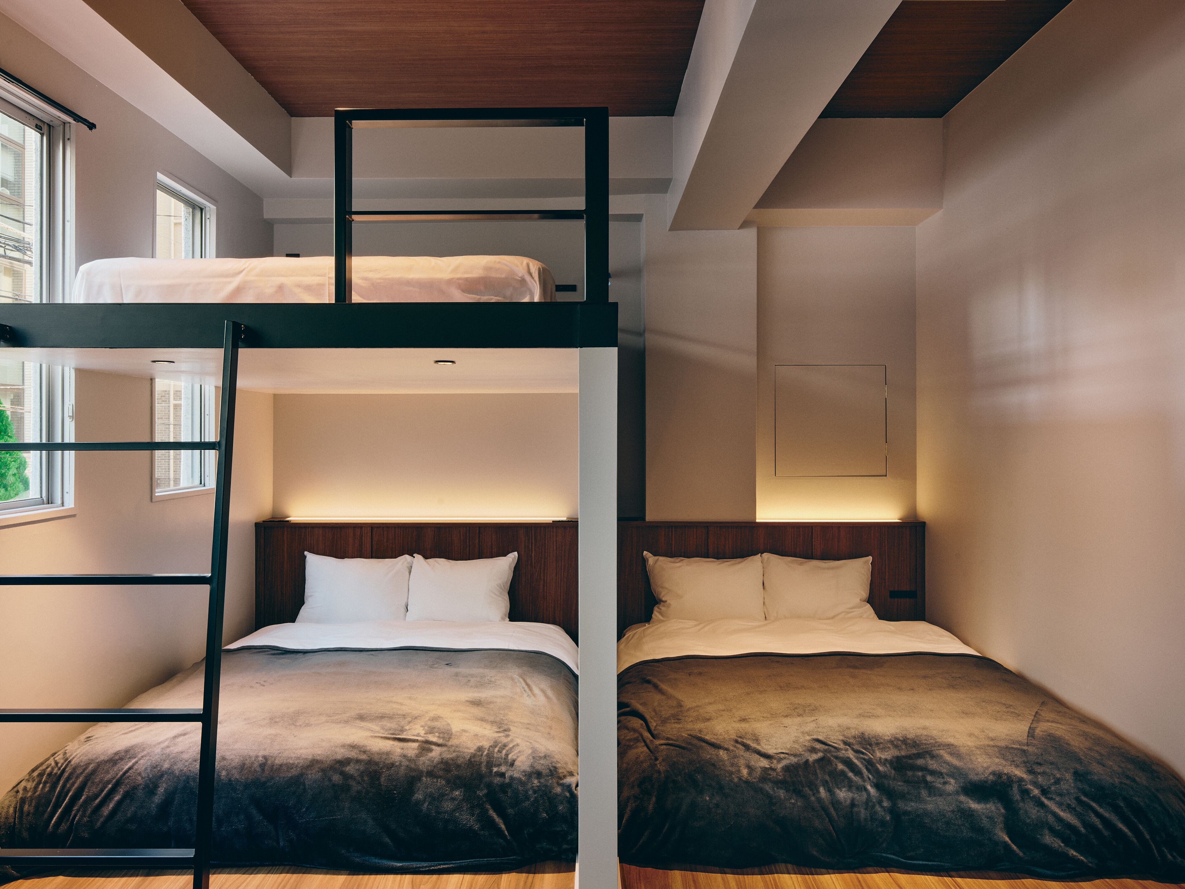 Quarto com beliche, teto de madeira, duas camas com roupa de cama branca e uma janela que proporciona iluminação natural.