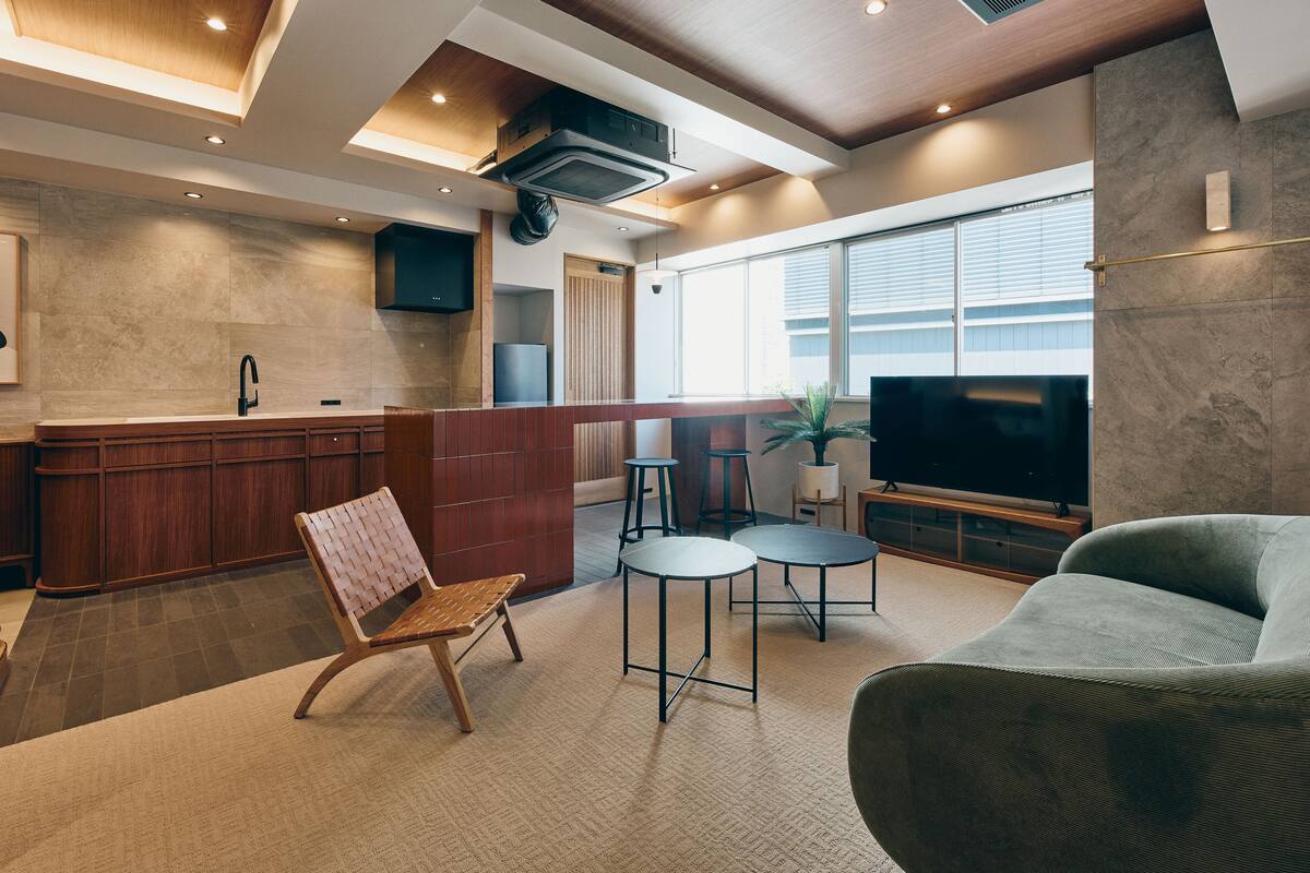 A modern living room with a kitchen area, a large TV, and a seating area with a coffee table.