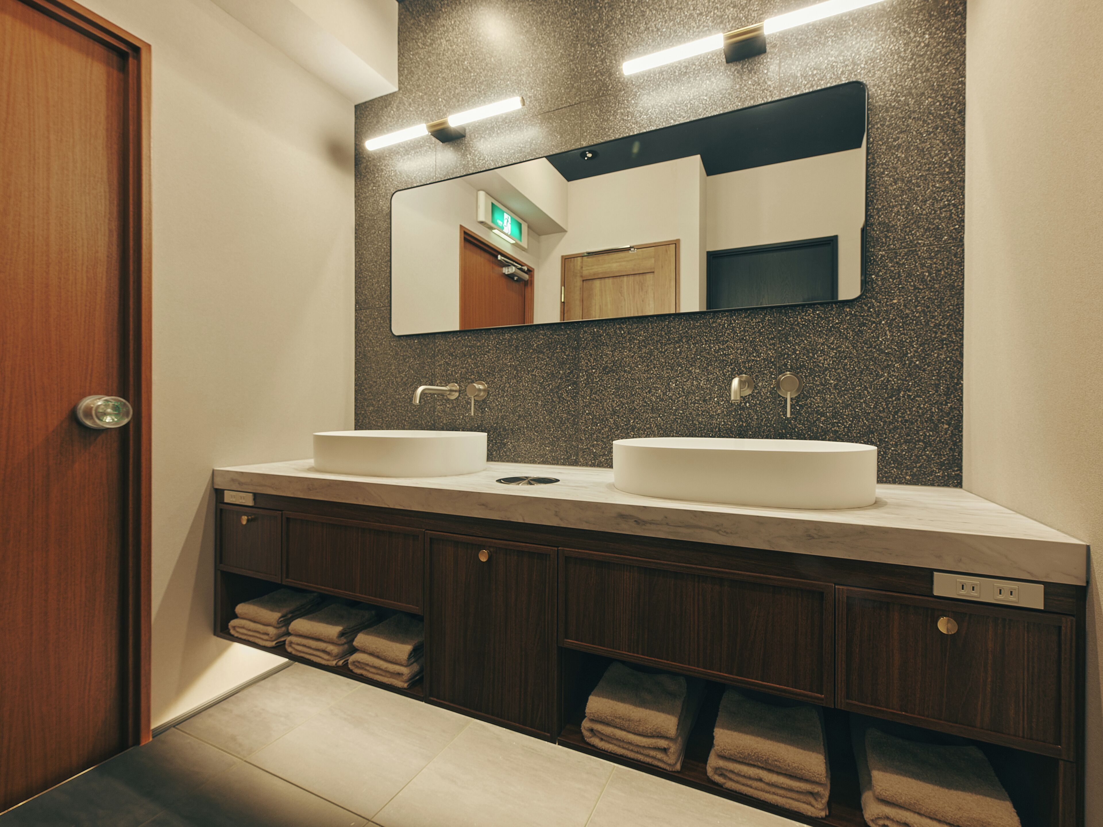 A modern bathroom with two sinks, a large mirror, and a towel rack.