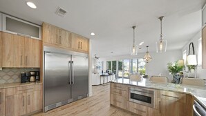 Una cocina moderna con armarios de madera, electrodomésticos de acero inoxidable e iluminación colgante.