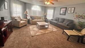 A living room with a ceiling fan, two couches, a coffee table, and a rug.