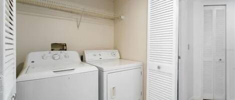A laundry room with two stacked washing machines and a drying rack.