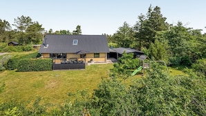 Une maison moderne avec un toit en pente, un patio et une pelouse bien entretenue.