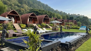 Una hilera de chalets de madera con piscina y zona de estar al aire libre.