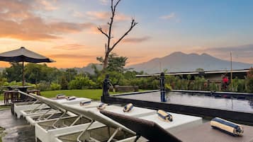 Una piscina al aire libre, sombrillas, sillones reclinables de piscina