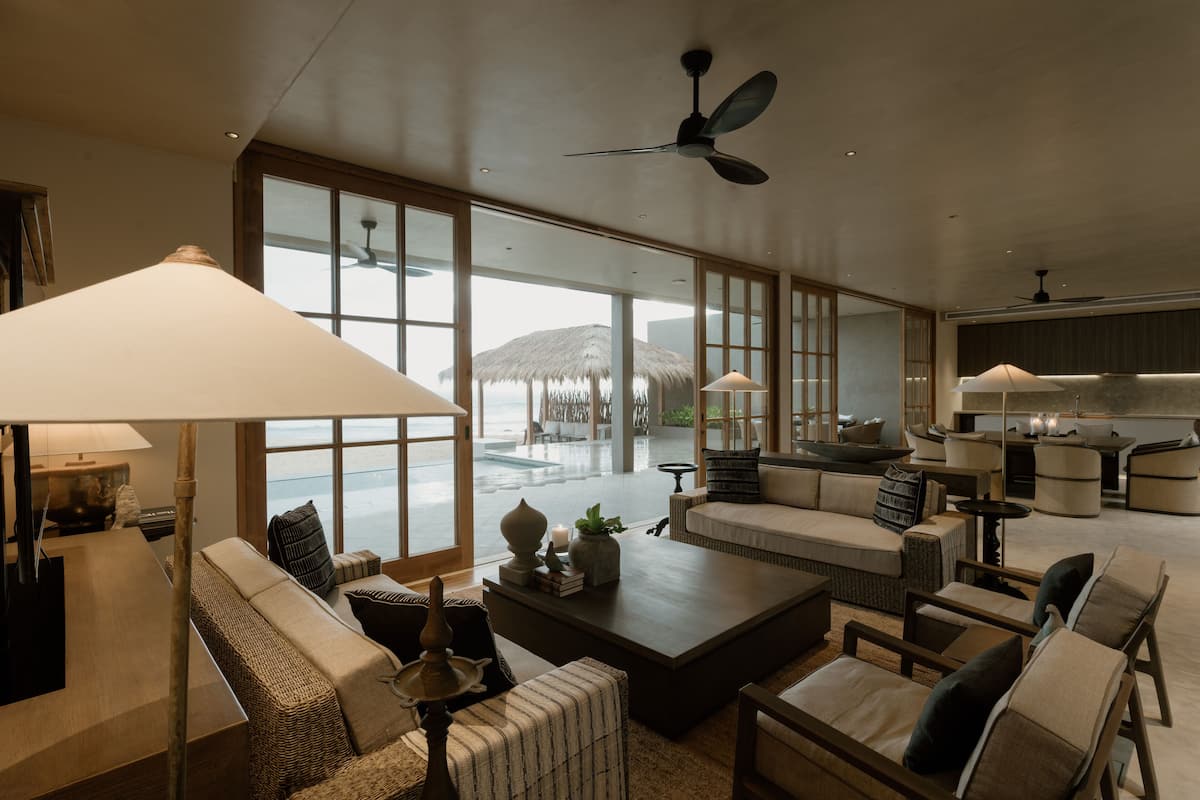 A spacious living area with large windows, a ceiling fan, and a view of the outdoor patio.