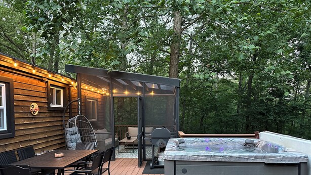 A wooden deck with a hot tub, outdoor seating, and string lights.