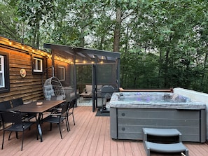 A wooden deck with a hot tub, outdoor seating, and string lights. - Hot Tub + Firepit + 20 Minutes to Luray Caverns + 35 Minutes to Skyline Drive (Luray)
