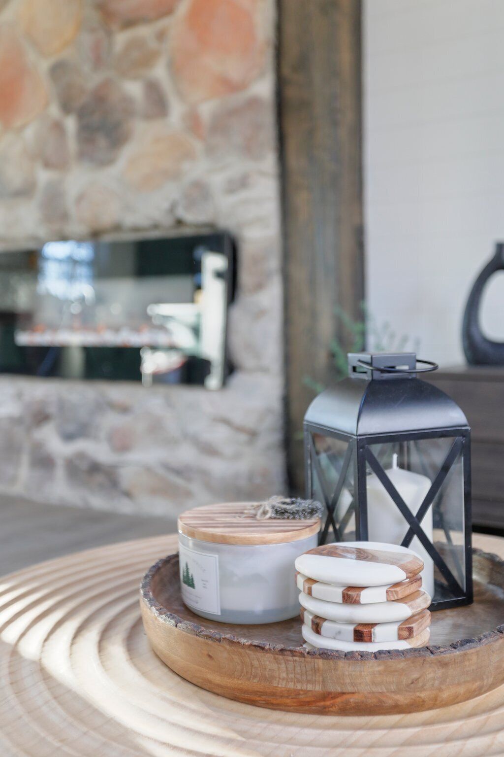 A wooden tray with two candles and a lantern on a stone wall background.