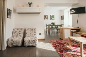 Una sala de estar moderna con un sofá, una mesa de centro, un televisor y un comedor con sillas y una mesa.