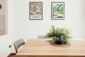 Un comedor con una mesa de madera, dos carteles enmarcados y una planta en maceta.