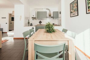 Una cocina moderna con una mesa de madera y sillas verdes, un comedor blanco y un pequeño centro de mesa con una planta.